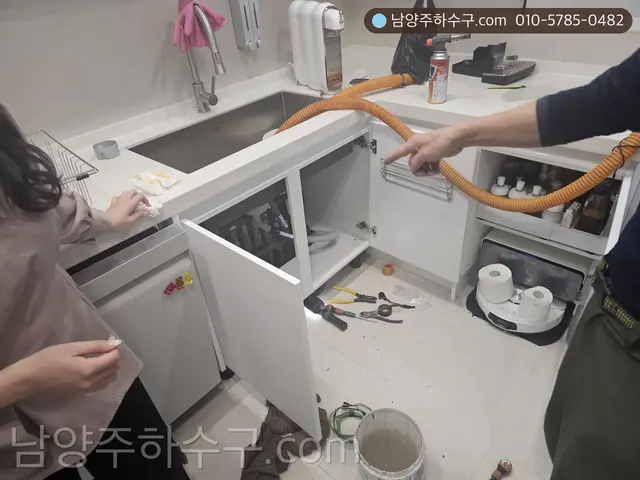 싱크대 하부장 안에서 배관 장비로 작업하는 모습